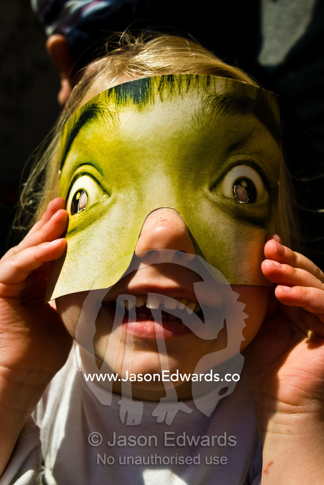A young girl plays with a paper mask at a children's birthday party. Fitzroy, Victoria, Australia.