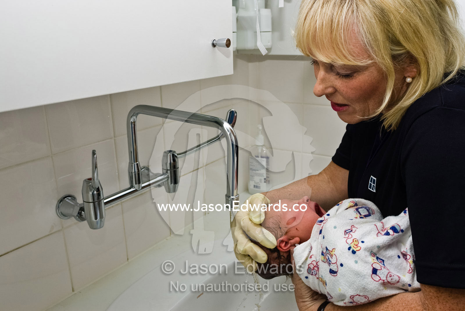 A nurse gently washes the hair of a newborn baby in warm water. Frances Perry House, Melbourne, Victoria, Australia.