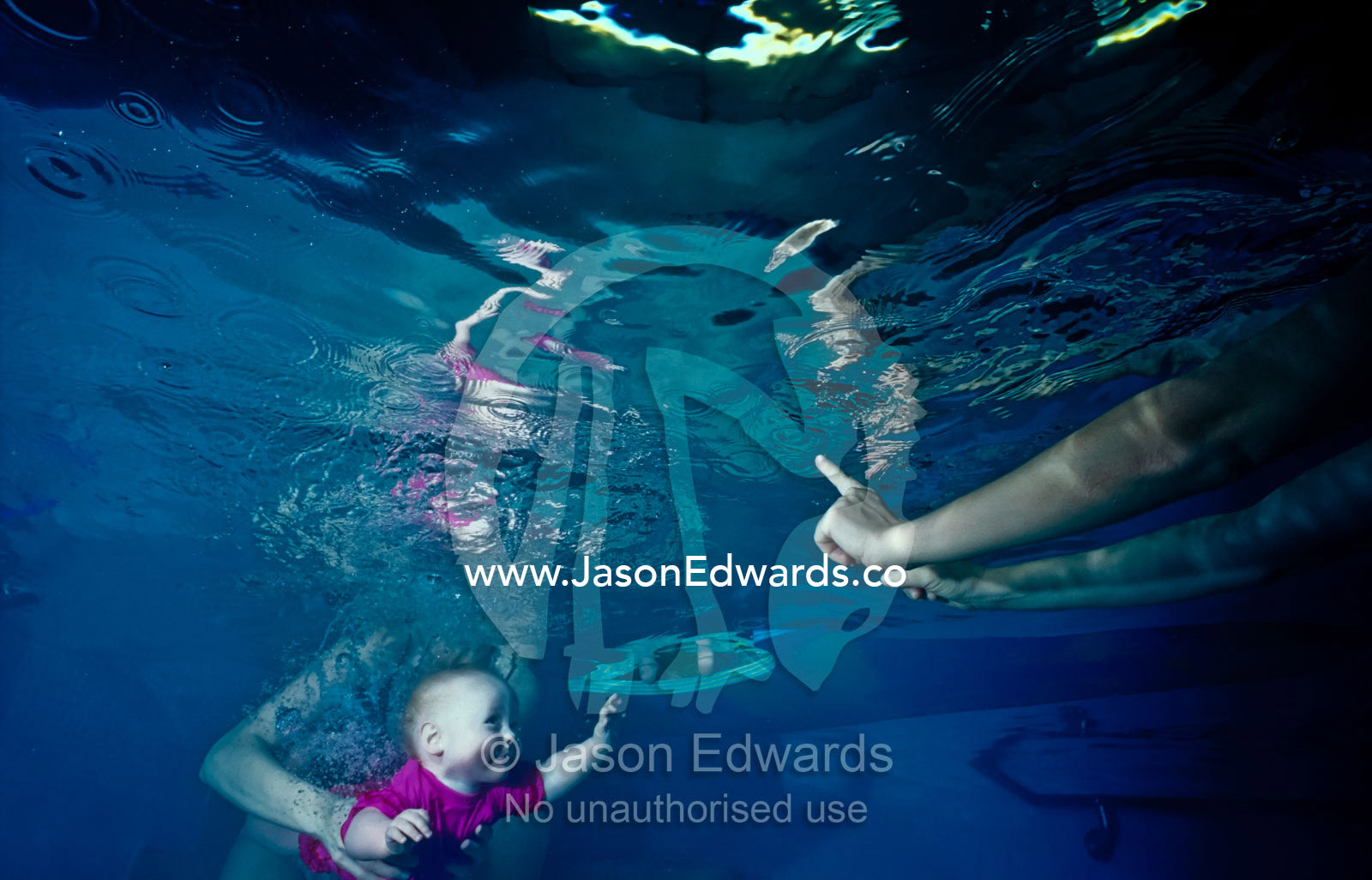 A baby reaches out for her mother's hands whilst learning to swim. Vaucluse Hospital, Brunswick, Victoria, Australia.