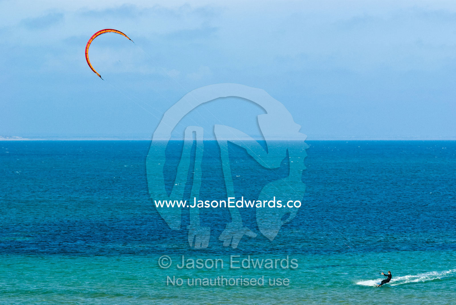 Kite surfers harness the onshore winds to race across a turquoise sea. Point Danger, Cosy Corner, Torquay, Victoria, Australia.