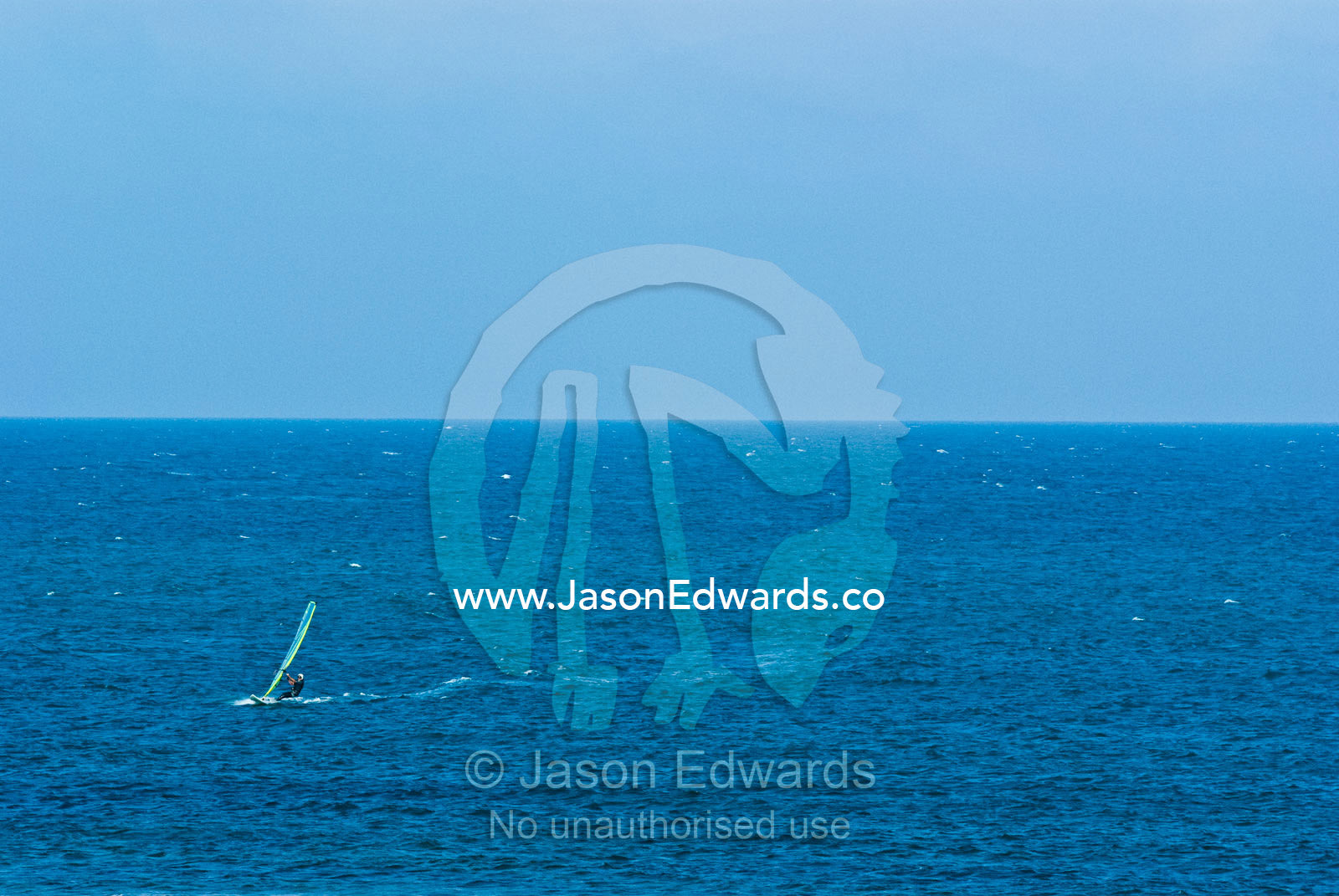 Windsurfers harness the onshore winds to race across a turquoise sea. Point Danger, Cosy Corner, Torquay, Victoria, Australia.