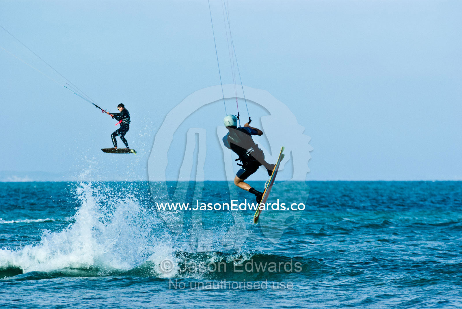 Kite surfers harness the onshore winds to launch over a turquoise sea. Point Danger, Cosy Corner, Torquay, Victoria, Australia.