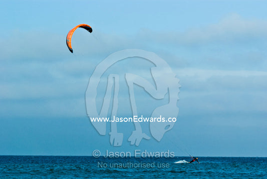 A kitesurfer races across a turquoise sea. Point Danger, Cosy Corner, Torquay, Victoria, Australia.