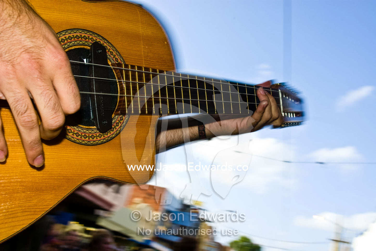 A musician's fingers strum the cords of a guitar during a public show. Brunswick Festival, Brunswick, Victoria, Australia.