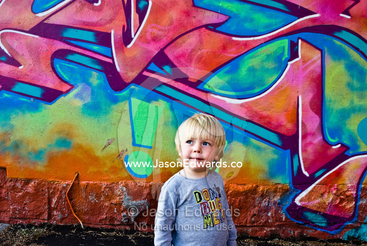 A thoughtful young boy next to graffiti on a house. North Carlton, Victoria, Australia.
