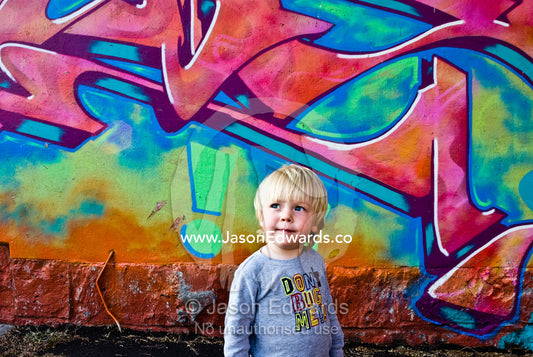 A thoughtful young boy next to graffiti on a house. North Carlton, Victoria, Australia.