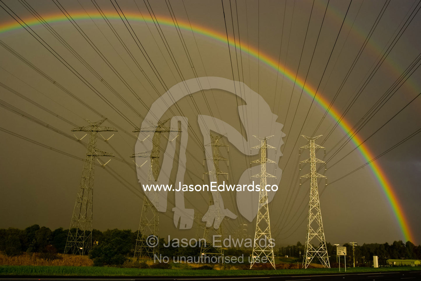 A vast array of electrical towers and cables beneath a huge rainbow. Eastern and Southeastern Suburbs, Melbourne, Victoria, Australia.