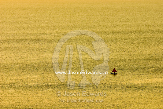 A small fishing boat heads out to sea at sunset for its nightly catch. Indian Ocean, Bukit Peninsula, Bali, Indonesia.