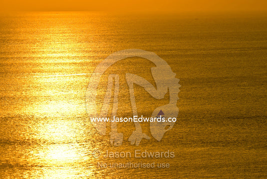 A small fishing boat heads out to sea at sunset for its nightly catch. Indian Ocean, Bukit Peninsula, Bali, Indonesia.