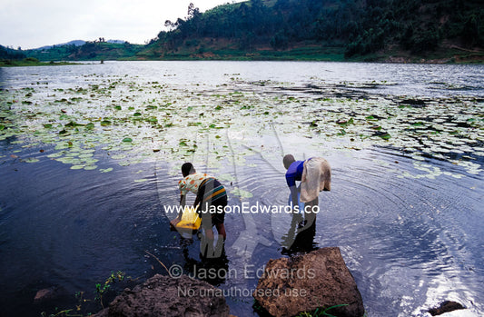 Teenage village girls collect fresh water from a volcano caldera lake. Lake Chahafi, Kisoro District, South Western Uganda.