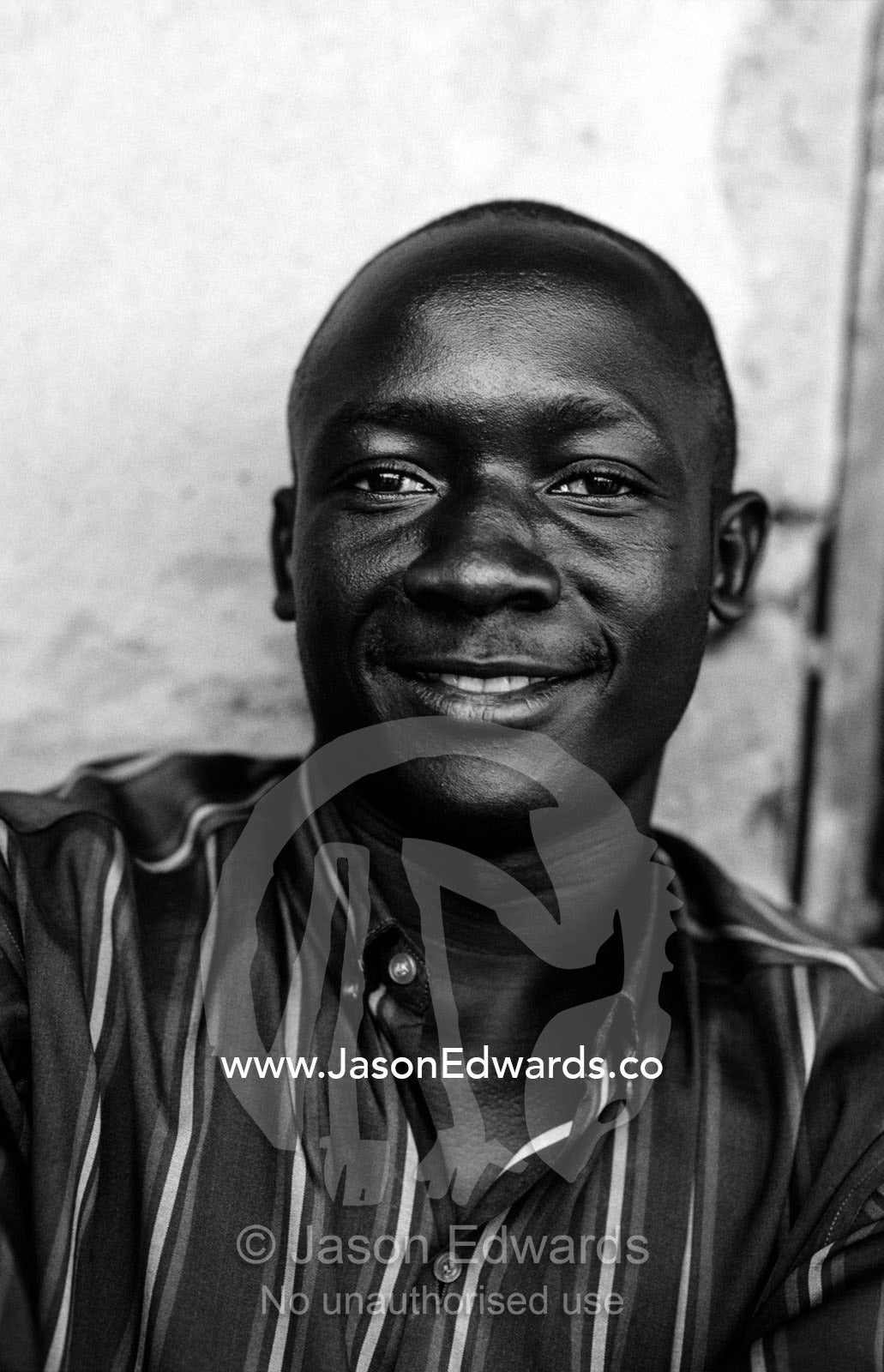 A smiling young East African man resting in a roadside truck stop. Tororo District, Eastern Uganda.