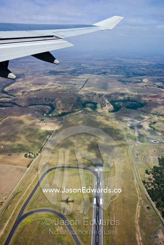 A jet airliner casts a shadow on a runway whilst preparing to land. Tullamarine Airport, Melbourne Victoria, Australia.