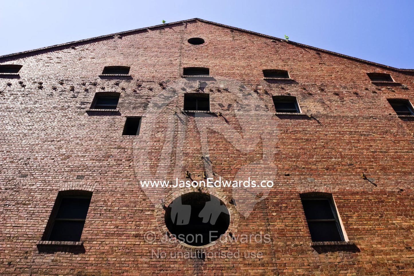 Dark shadowed windows in the facade of a restored colonial factory. Melbourne, Victoria, Australia.