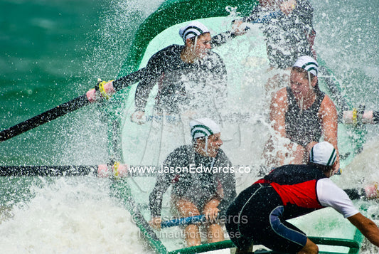 Women row a surf boat through raging seas at the Australian Titles. Australian Surfboat Open Titles, Fishermen's Bay, Torquay, Victoria, Australia.