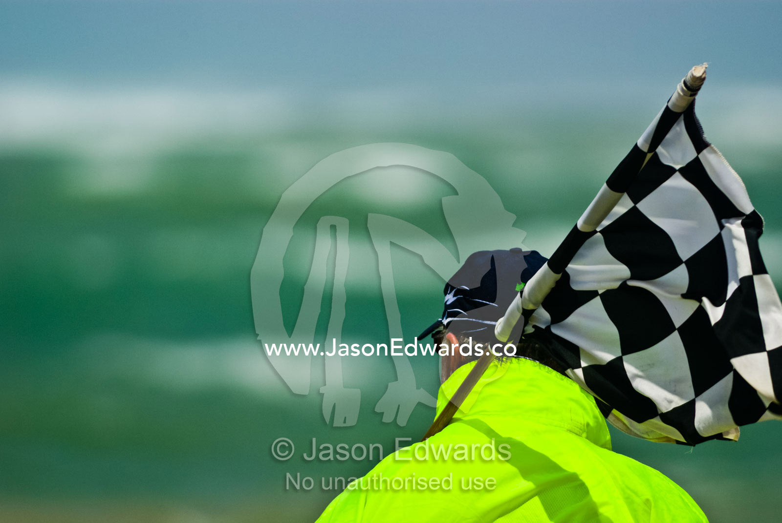 A steward prepares to wave a chequered flag to start a surf boat race. Australian Surfboat Open Titles, Fishermen's Bay, Torquay, Victoria, Australia.