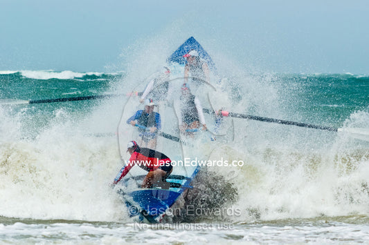 Women row a surf boat through raging seas at the Australian Titles. Australian Surfboat Open Titles, Fishermen's Bay, Torquay, Victoria, Australia.