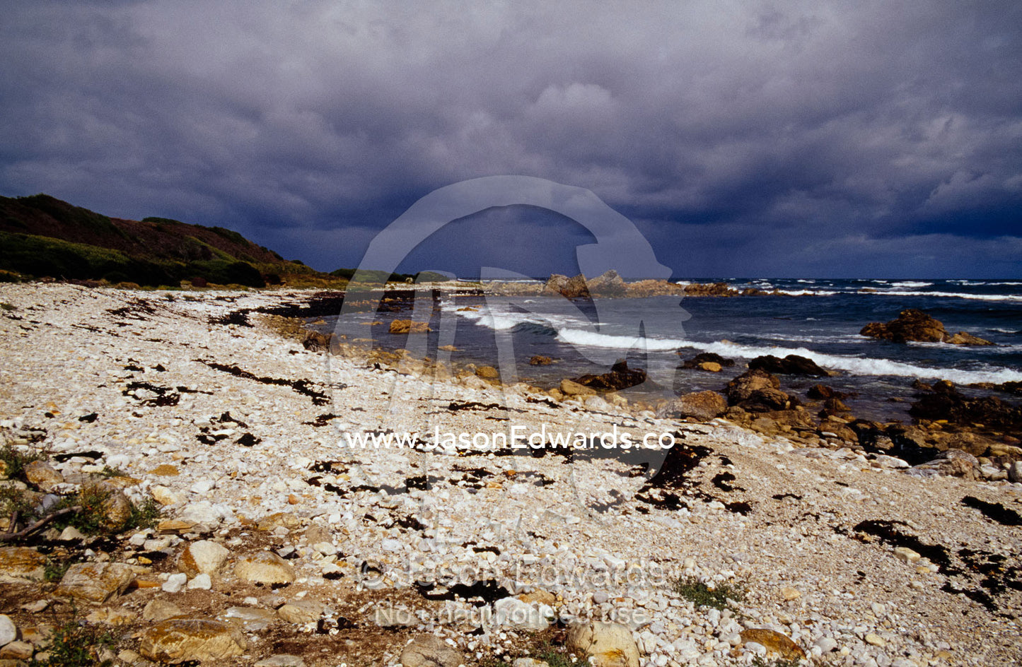A storm rolls in over a rugged stony beach along the Southern Ocean. South West Conservation Area, Tasmania, Australia.
