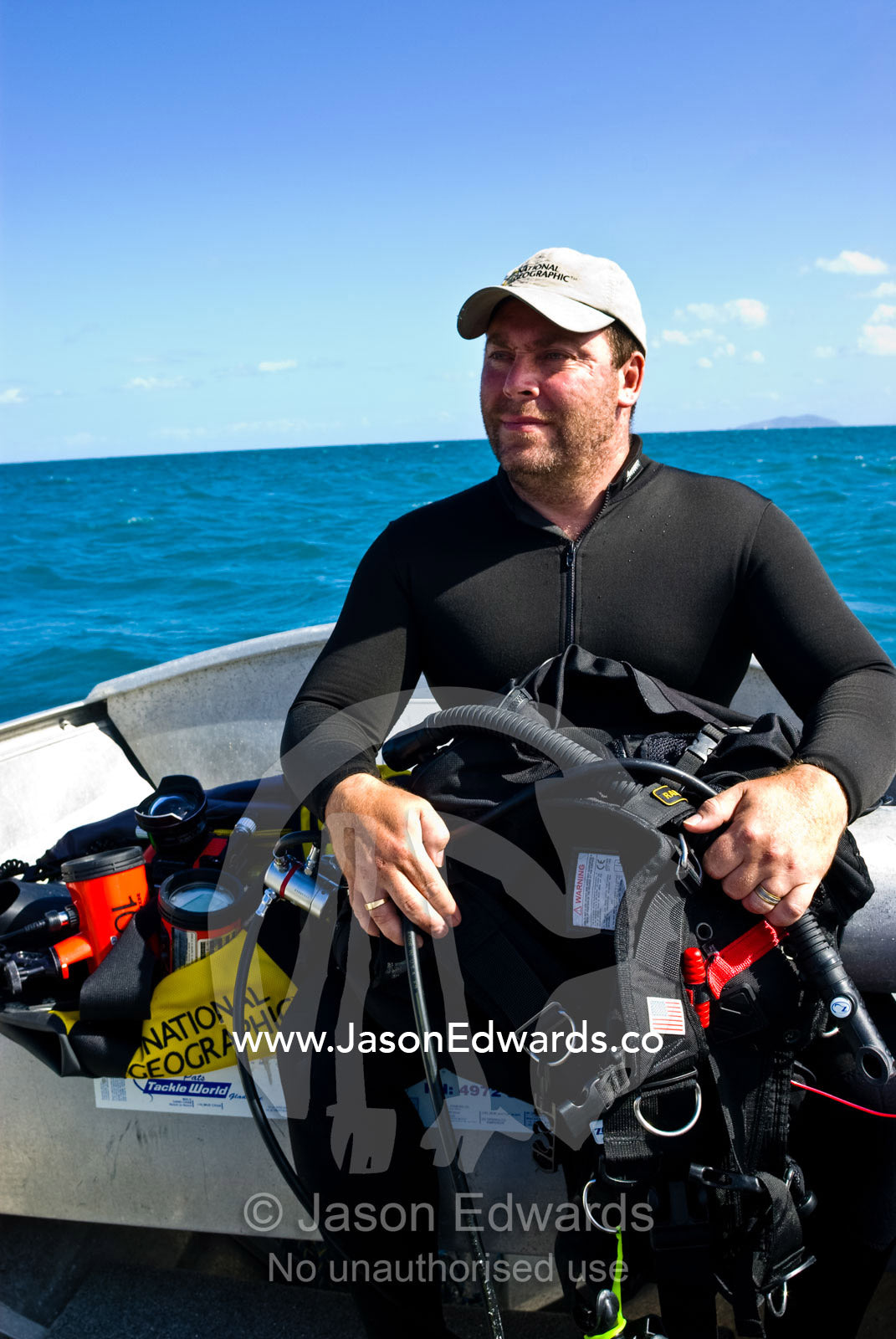 A scuba diver and underwater photographer waits in a small boat. South Molle Island, Whitsunday Islands, Queensland, Australia.