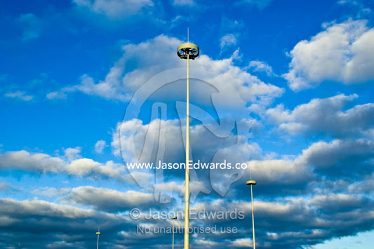 Modern needle-like highway lighting rising into a cloud-filled sky. West Gate Freeway and Princes Freeway Interchange, Laverton, Victoria, Australia