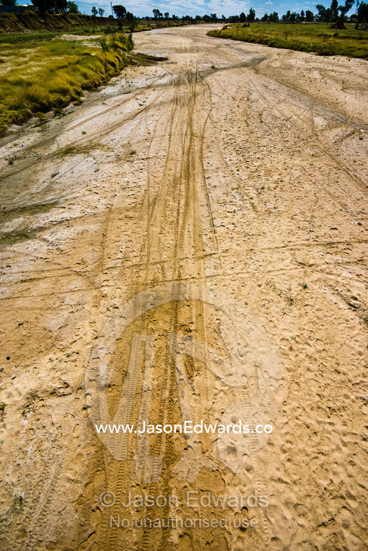 Footprints and tyre tracks scar the sands of the Flinders River bed. Flinders River, Hughenden, Queensland, Australia