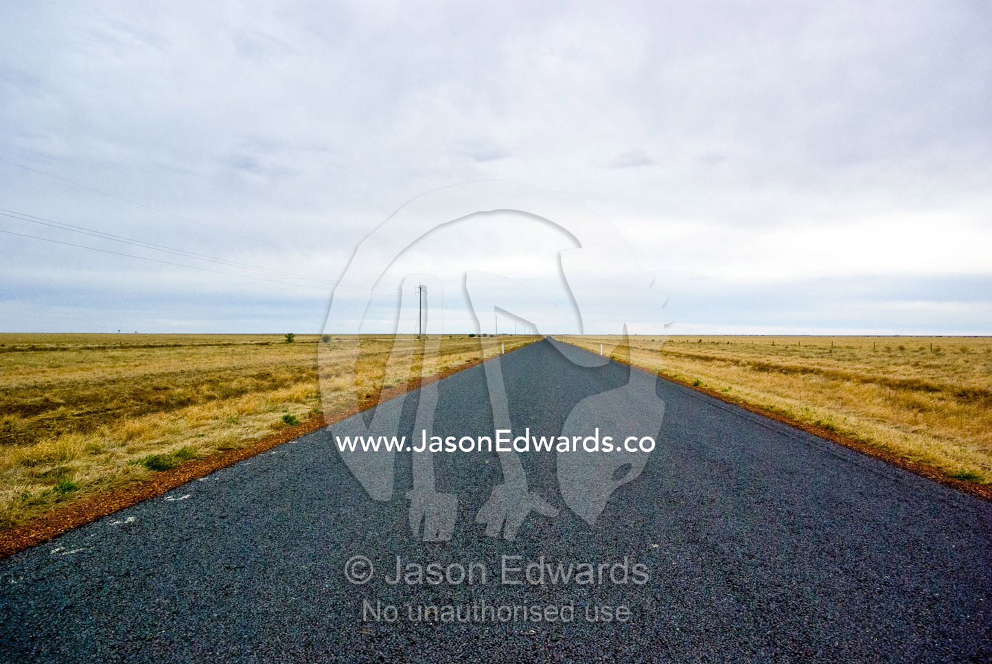 A grey storm rolls over a featureless plain and remote outback road. Kennedy Developmental Road, near Hughenden, Queensland, Australia