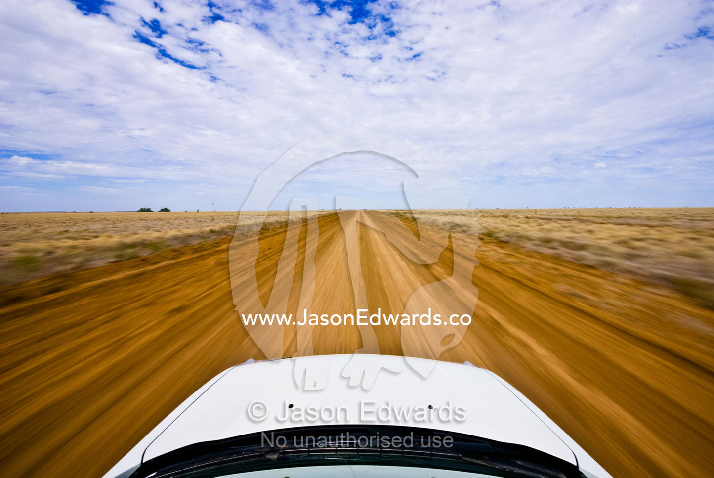 An SUV drives at high speed along a rough dirt road in the Outback. Hughenden Muttaburra Road, Queensland, Australia
