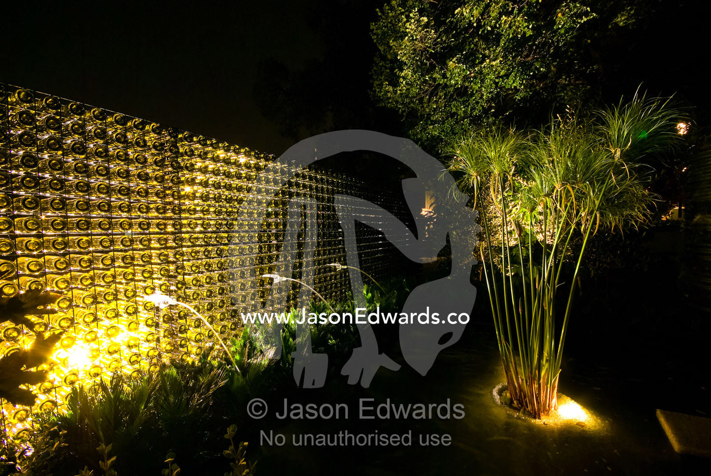 Ornamental lighting illuminates a fountain pond and wine bottle wall. Melbourne International Flower and Garden Show 2009, Carlton Gardens, Melbourne, Victoria, Australia