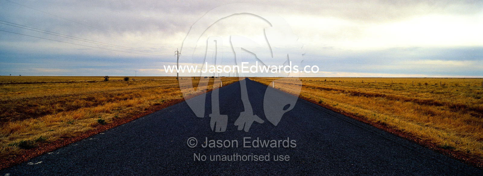 A grey storm rolls over a featureless plain and remote outback road. Kennedy Developmental Road, near Hughenden, Queensland, Australia