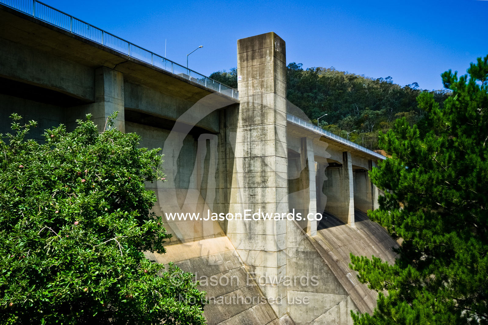 The imposing concrete wall, chutes and support tower of a dam wall. Eildon Weir Spillway, Lake Eildon, Victoria, Australia.