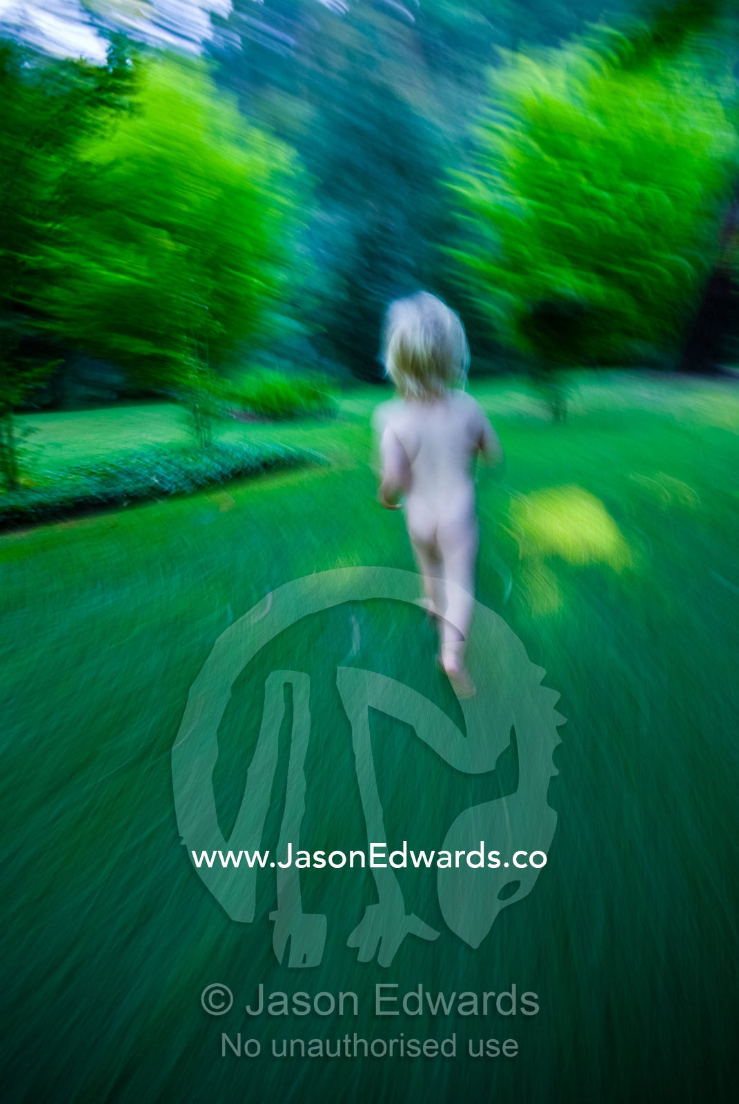 A toddler runs naked through a country garden on a summer afternoon. Upper Goulburn River, Jamieson, Victoria, Australia.