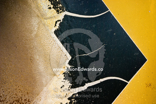 A fire damaged metal safety sign on a bend in a country road. Junction Ridge Road, near Kinglake National Park, Victoria, Australia