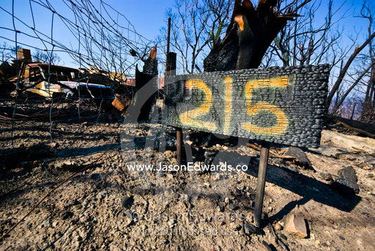 A house number replaced on a burnt sign using fluorescent spray paint. Bald Spur Road, Kinglake National Park, Victoria, Australia