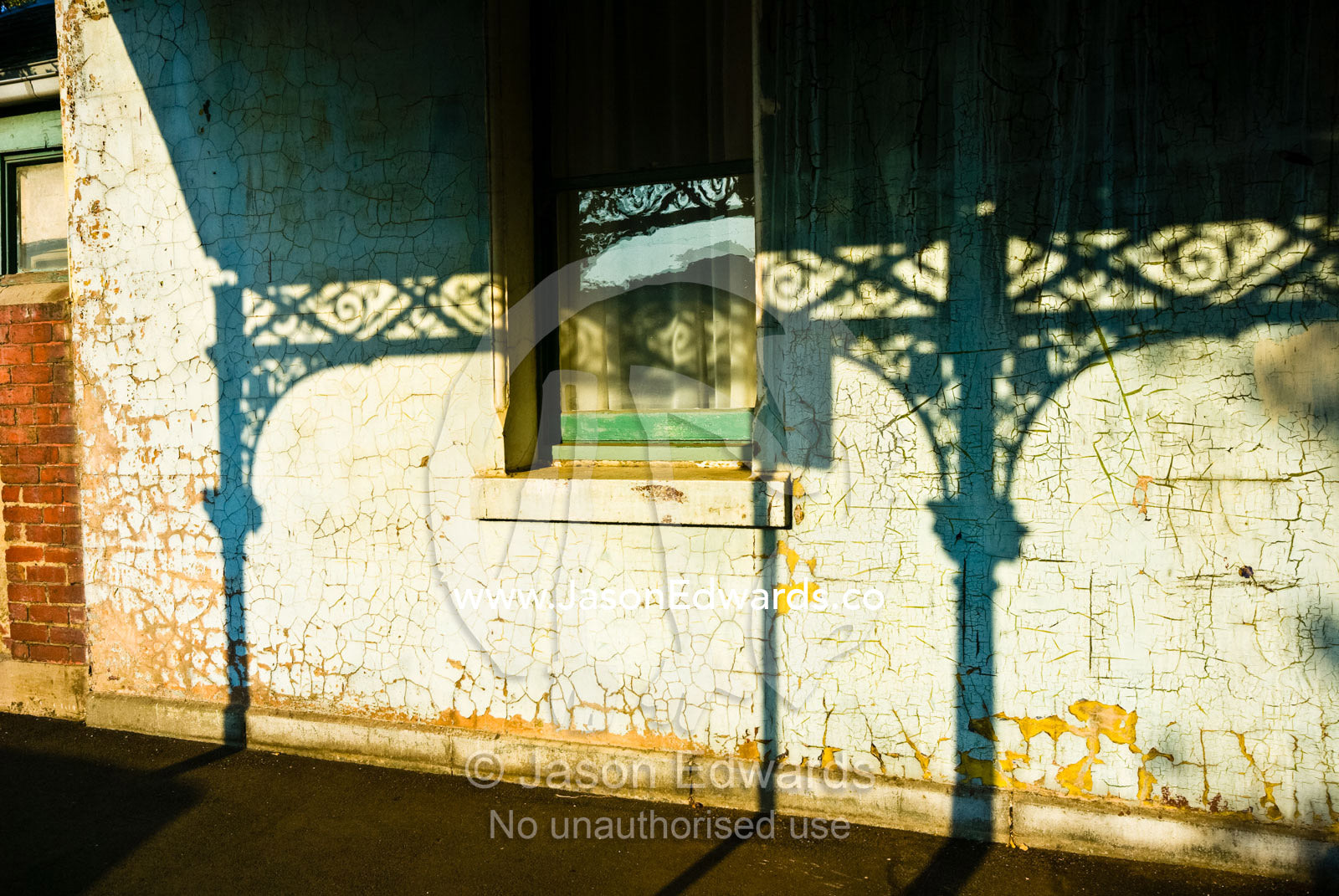 Afternoon sun casts shadows of a Victorian era steel lattice on a wall North Carlton, Victoria, Australia