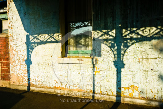 Afternoon sun casts shadows of a Victorian era steel lattice on a wall North Carlton, Victoria, Australia