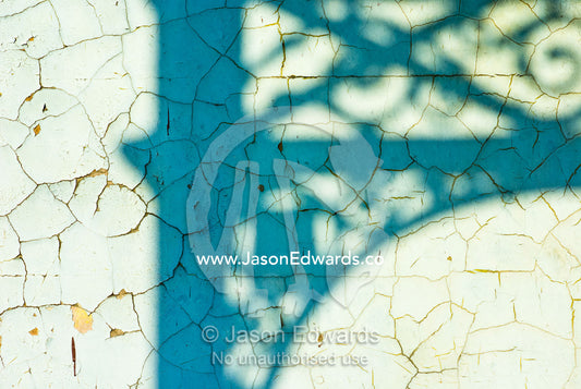 Afternoon sun casts shadows of a Victorian era steel lattice on a wall North Carlton, Victoria, Australia