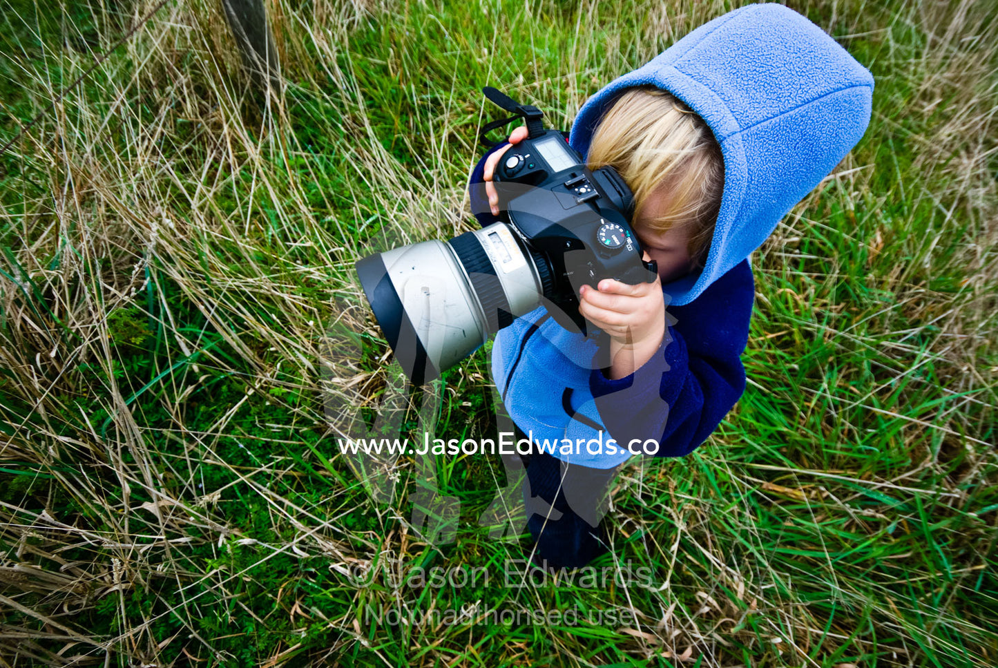 A small boy learning to take photographs in a farm field in winter. near Fish Creek, Victoria, Australia