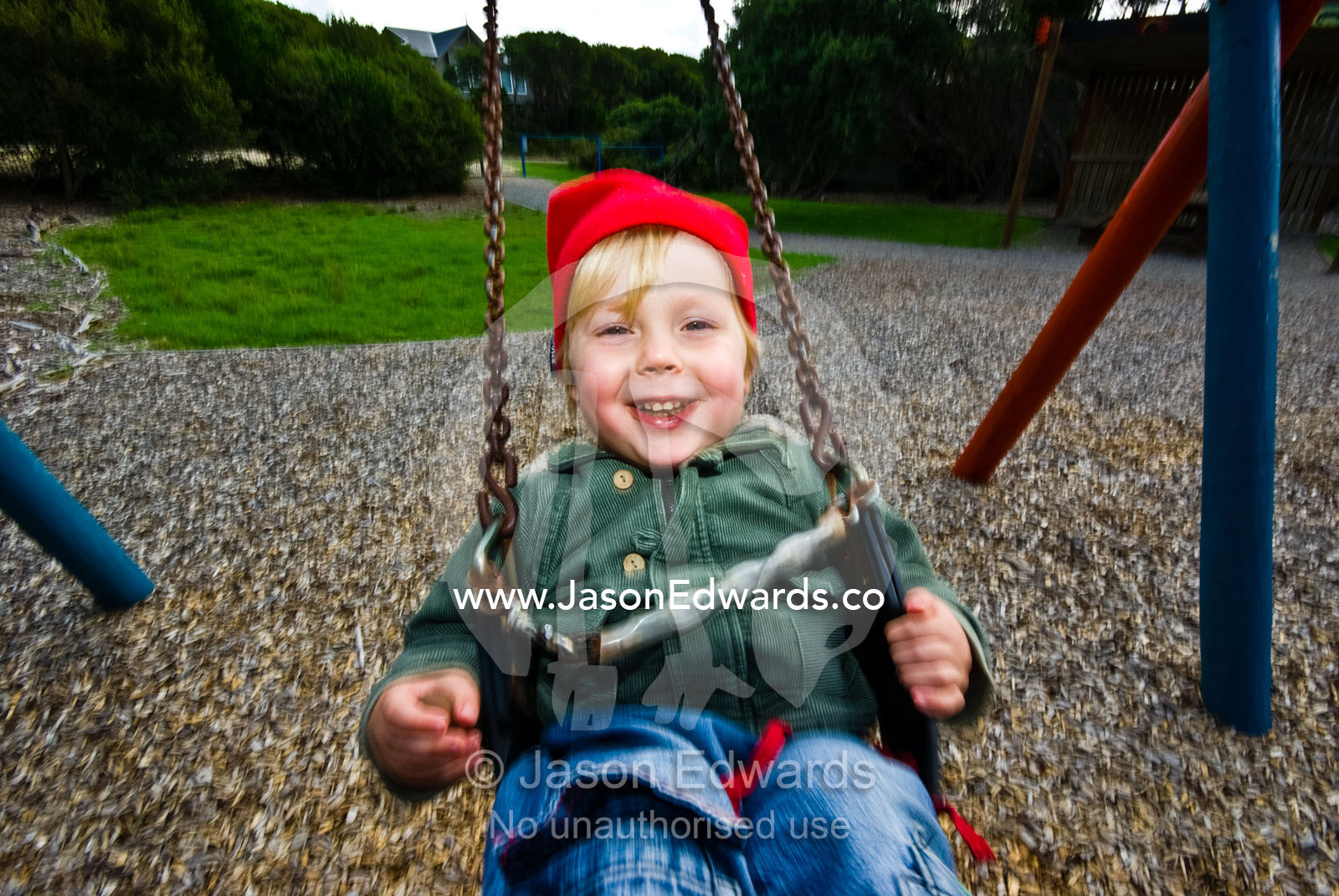 A young boy laughing hysterically as he plays on a swing in a park. Sandy Point, Victoria, Australia