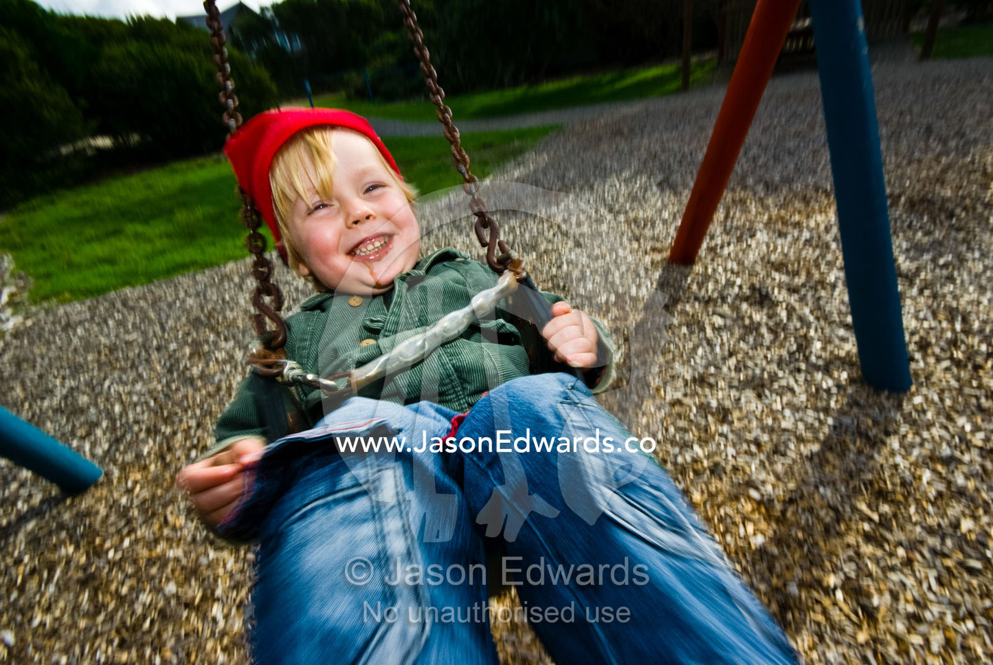 A young boy laughing hysterically as he plays on a swing in a park. Sandy Point, Victoria, Australia