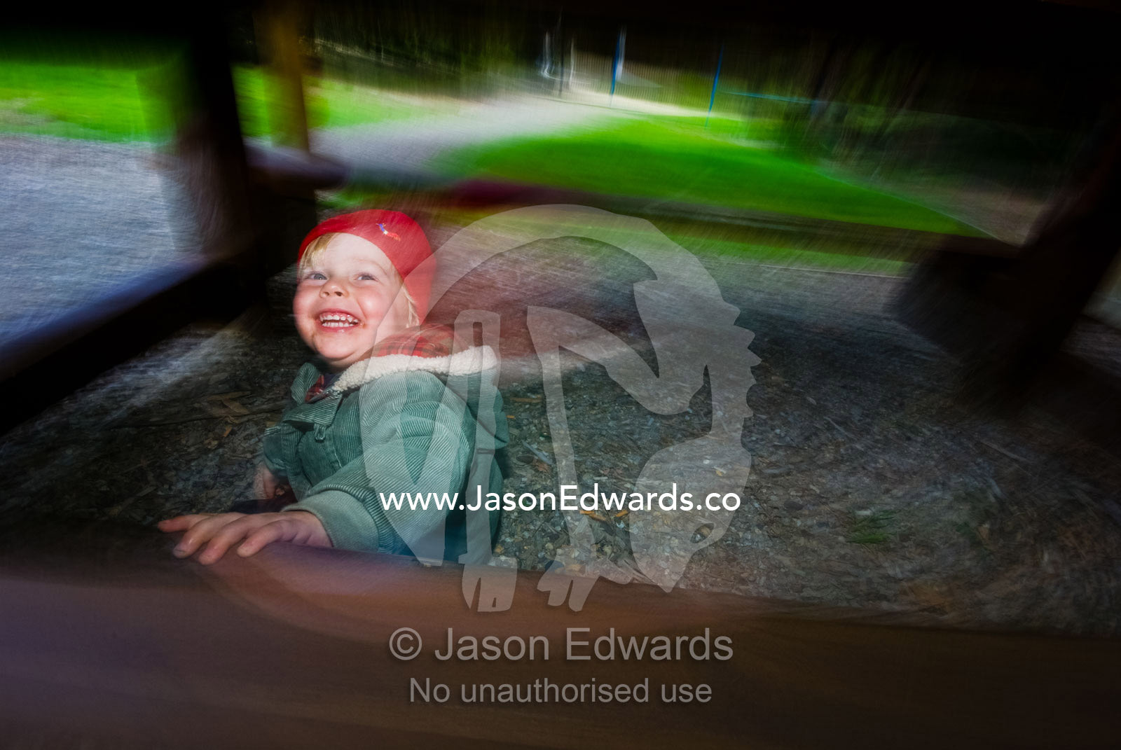 A young boy laughing hysterically as he plays under a picnic table. Sandy Point, Victoria, Australia