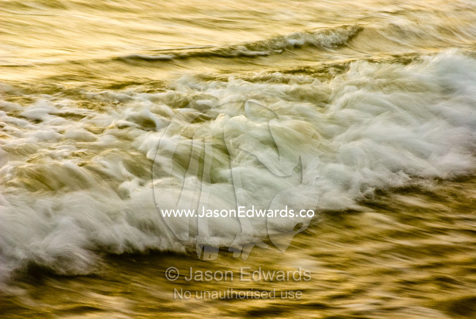 The lip of a foaming wave flows towards the shore at twilight. Waratah Bay, Victoria, Australia.