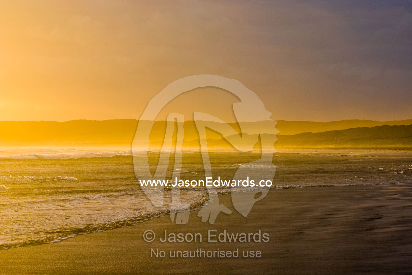 Small waves caress a wide beach in an ocean bay at sunset. Waratah Bay, Victoria, Australia.