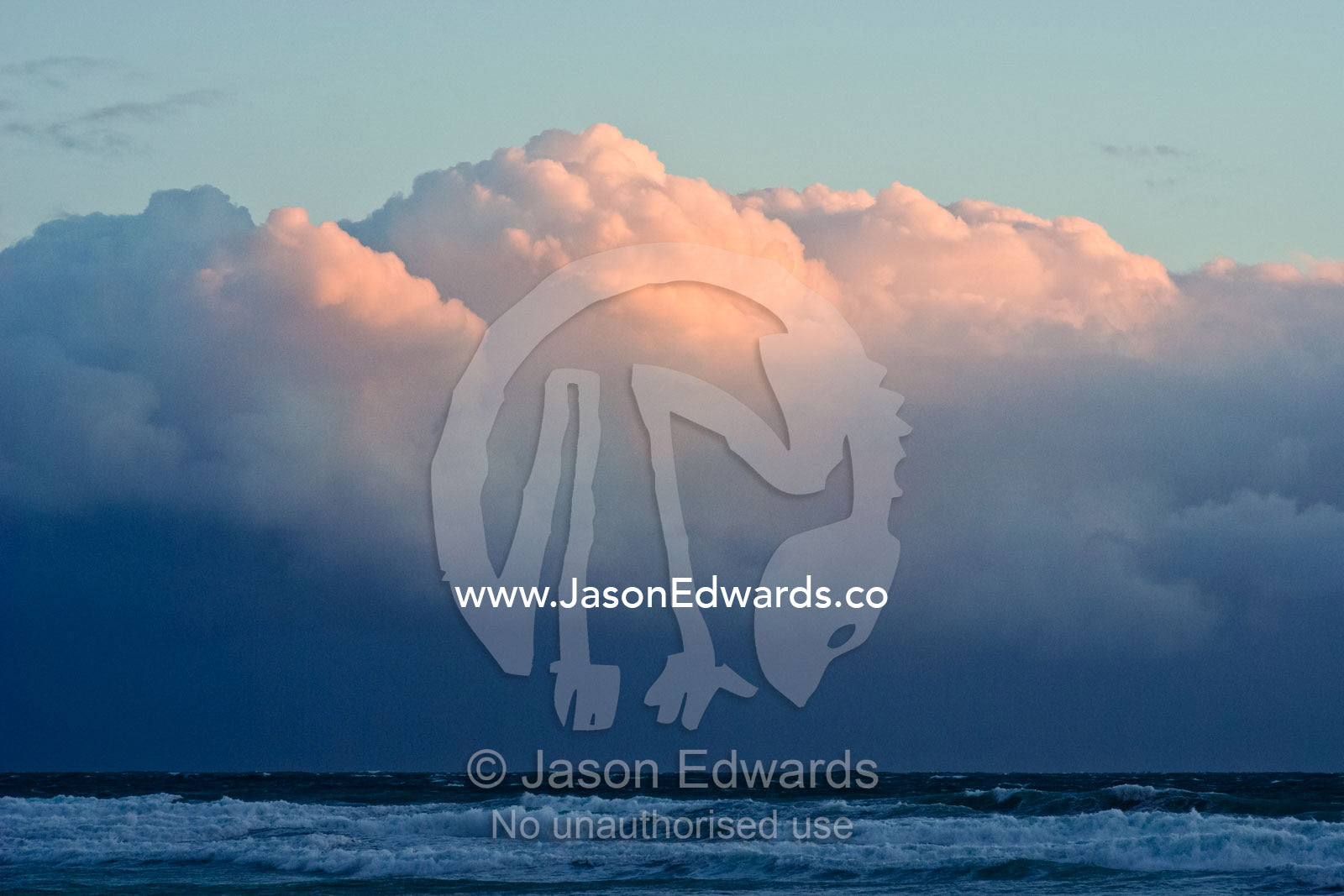 The looming thunderheads of an ocean storm turn pastel pink at sunset. Waratah Bay, Victoria, Australia.