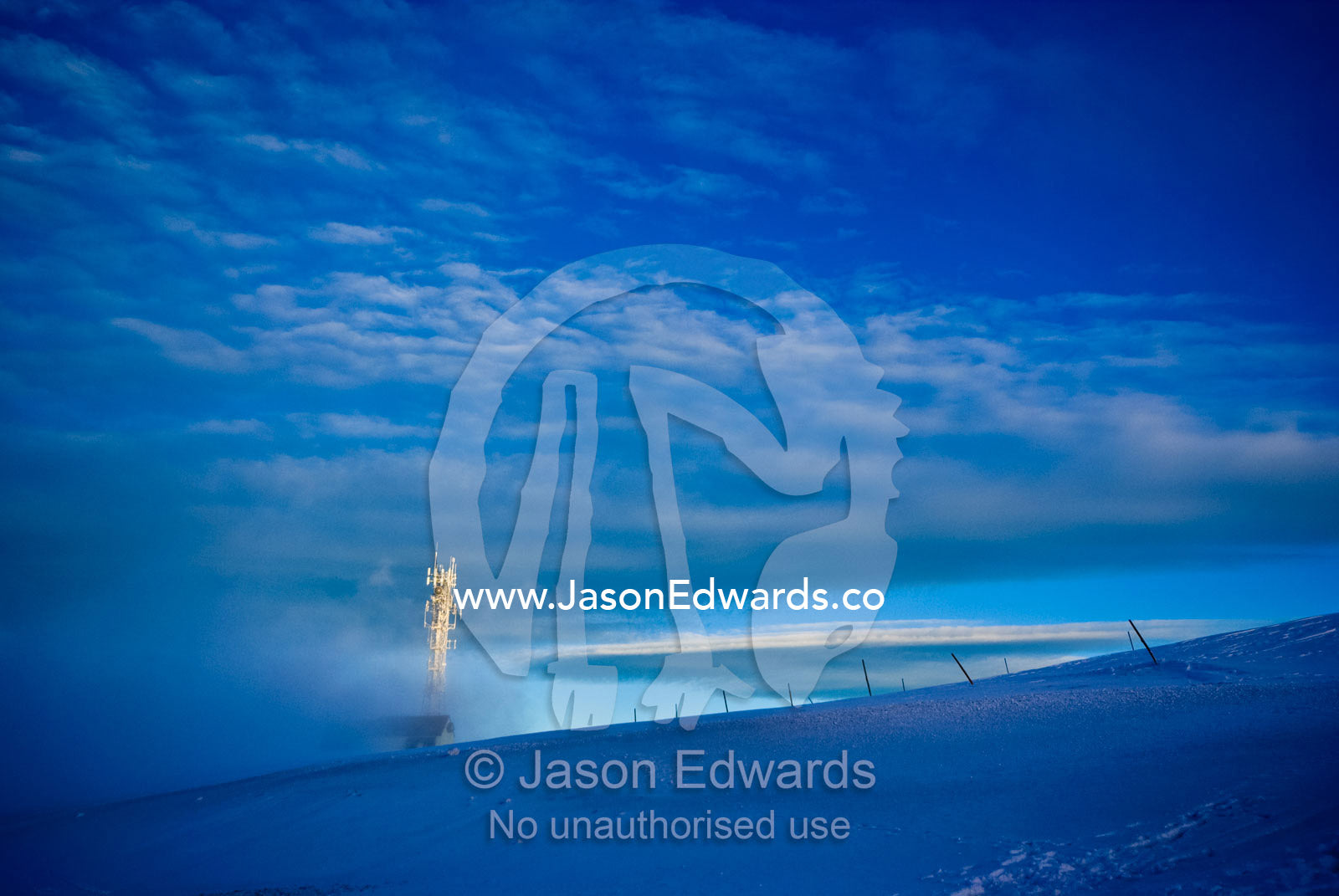 A mobile phone tower rises above the clouds on a snowy mountaintop. Mount Hotham, Victoria, Australia.