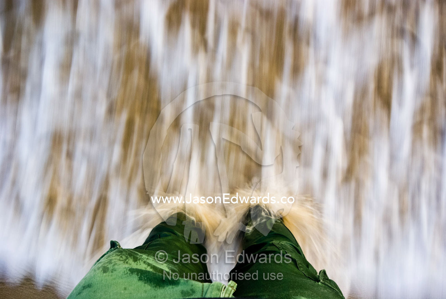 Ocean waves crash in against a mans legs standing in the shallow water Sandy Point, Victoria, Australia