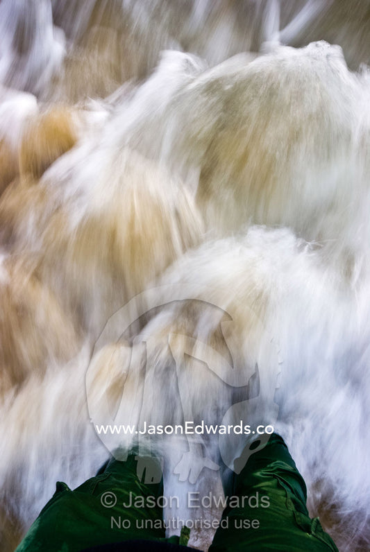 Ocean waves crash in against a mans legs standing in the shallow water Sandy Point, Victoria, Australia
