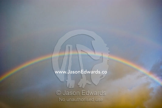 A rainbow arches over storm clouds on a winters afternoon. Sandy Point, Victoria, Australia