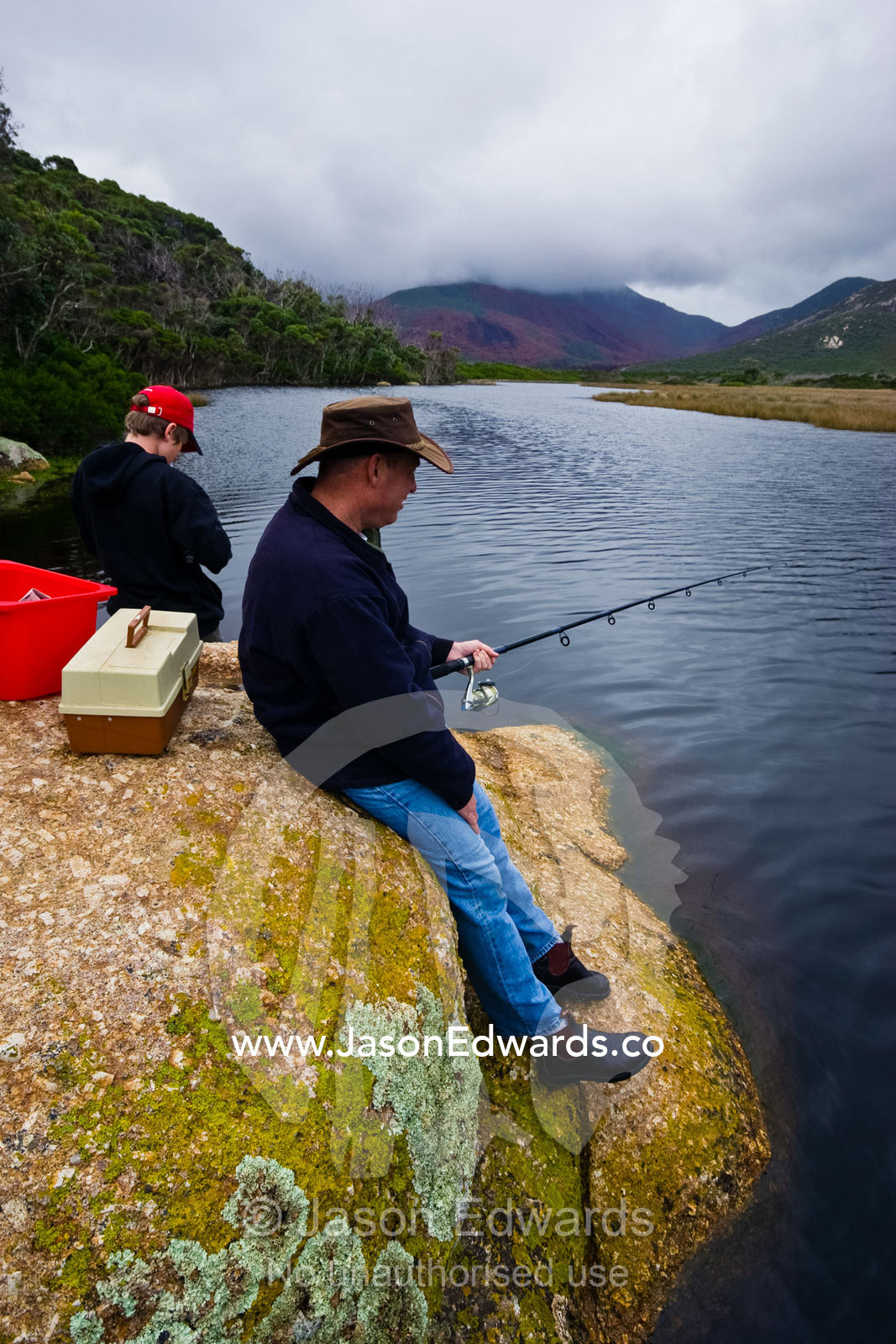 A father and son fishing in a small coastal river on a winters day. Tidal River, Wilsons Promontory National Park, Victoria, Australia