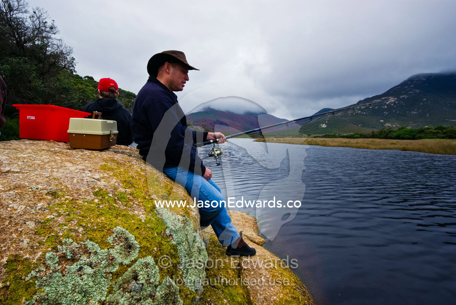 A father and son fishing in a small coastal river on a winters day. Tidal River, Wilsons Promontory National Park, Victoria, Australia