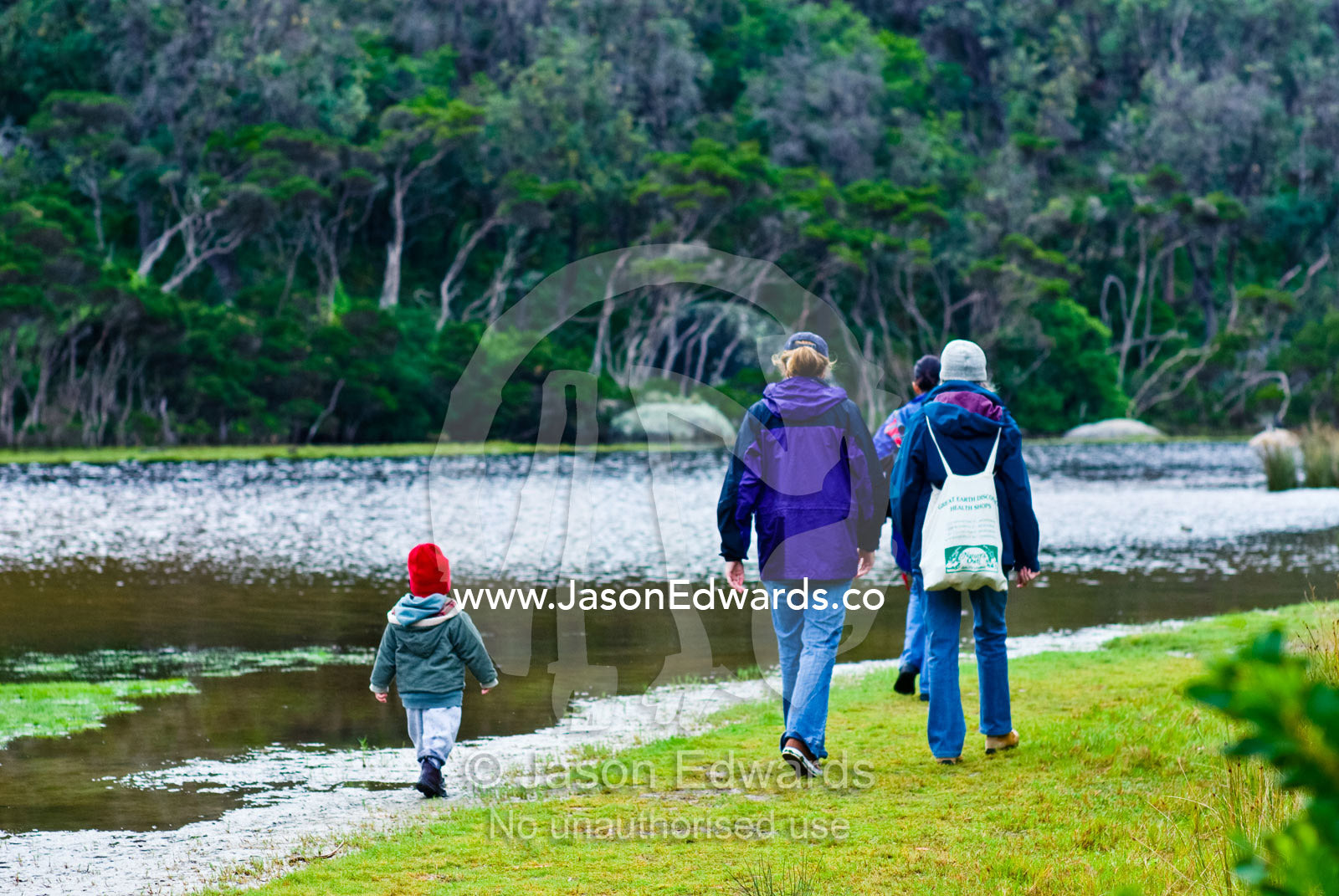 A small boy follows his mother and grandmother on a walk by a river. Tidal River, Wilsons Promontory National Park, Victoria, Australia