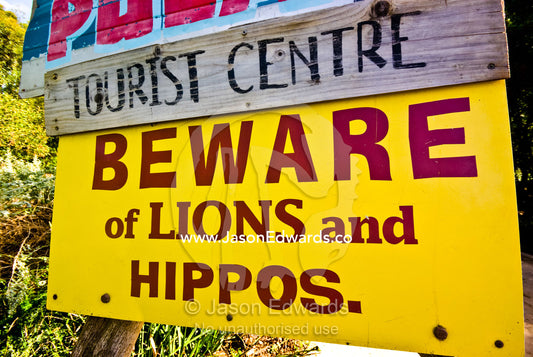 A colorful sign warns tourists of danger from lions and hippopotamus. Werribee Open Range Zoo, Werribee, Victoria, Australia
